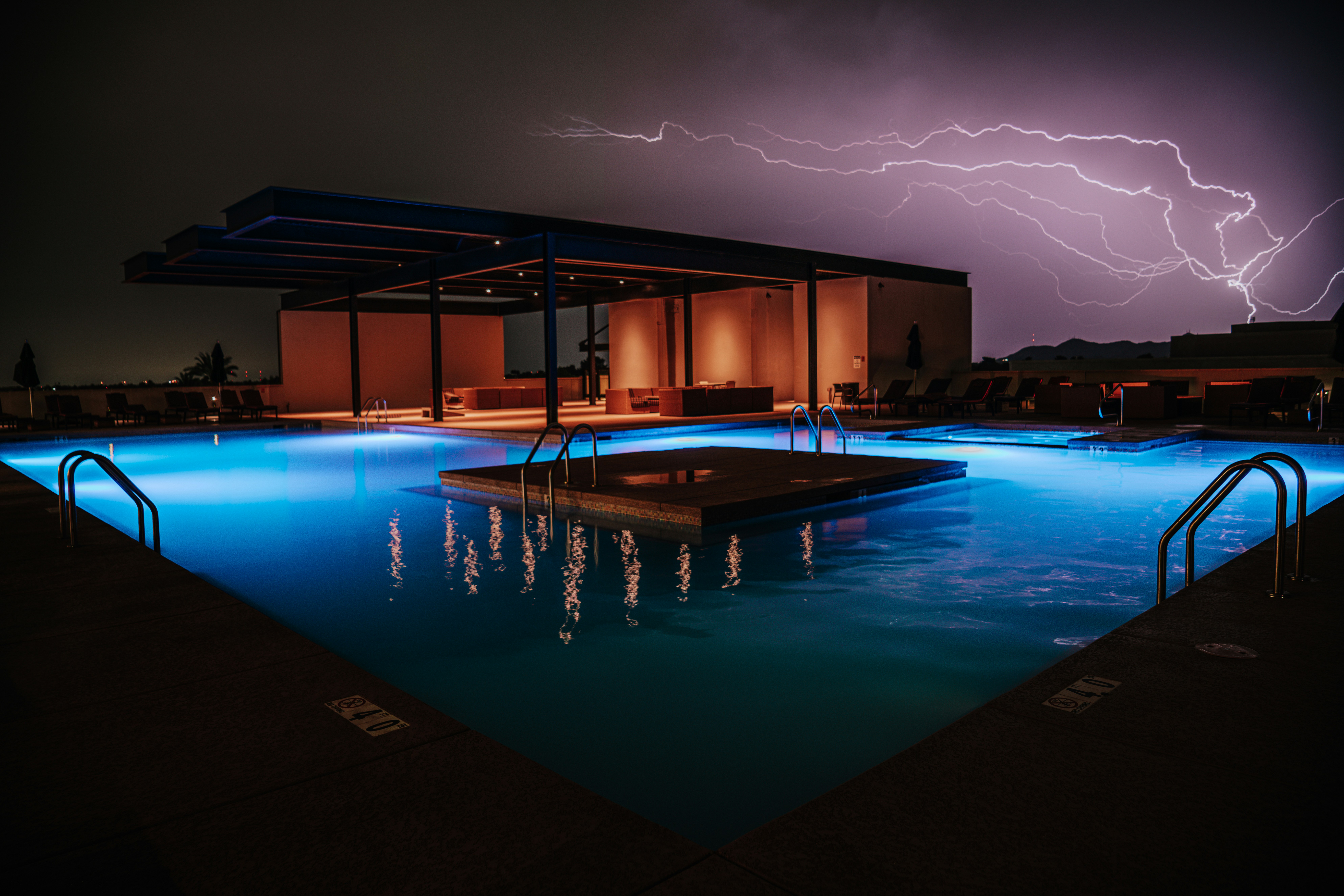 A pool with a lightning storm in the background
